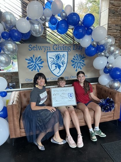 Selwyn students seated in front of a Selwyn Giving Day backdrop framed by a balloon arch